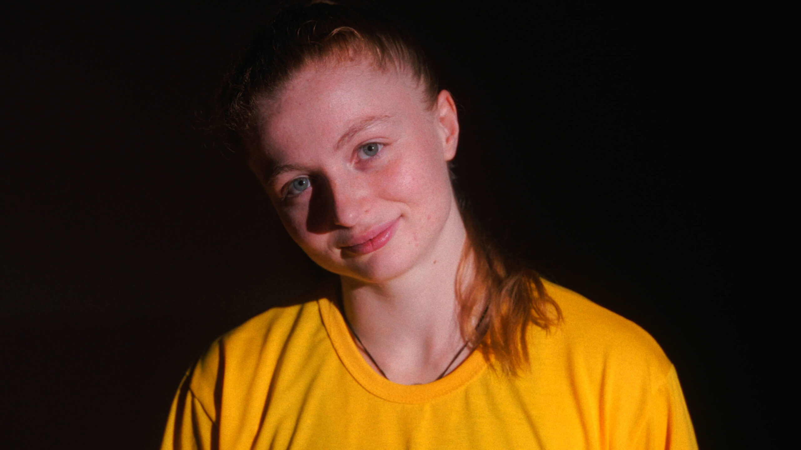 Portrait de Mahrie Corbu en tee-shirt jaune sur fond noir, dans le documentaire Passion Is Always Right
